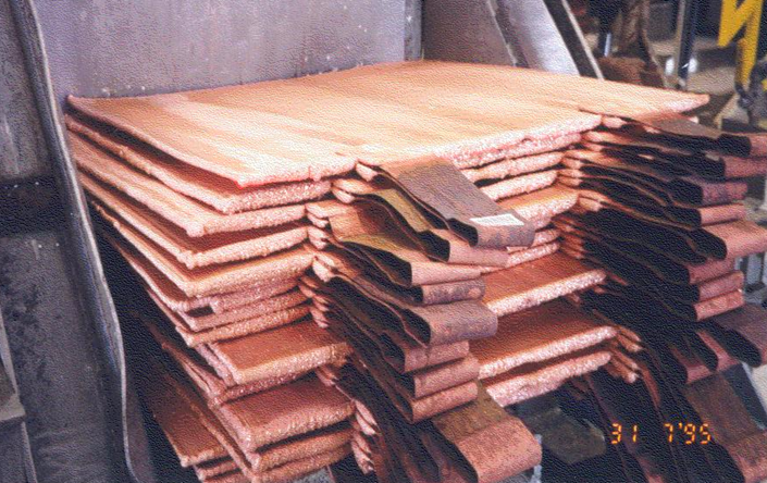 Stacked copper cathode sheets inside a copper refinery.