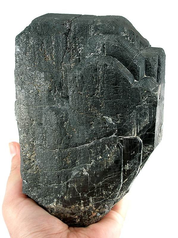 A large natural tantalite mineral specimen, held in a hand for scale.