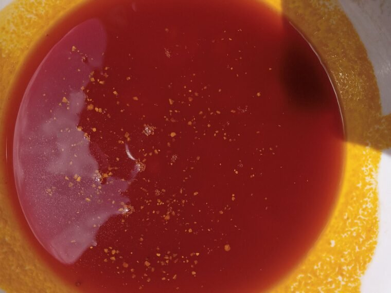 Red palm oil photographed in a white bowl.