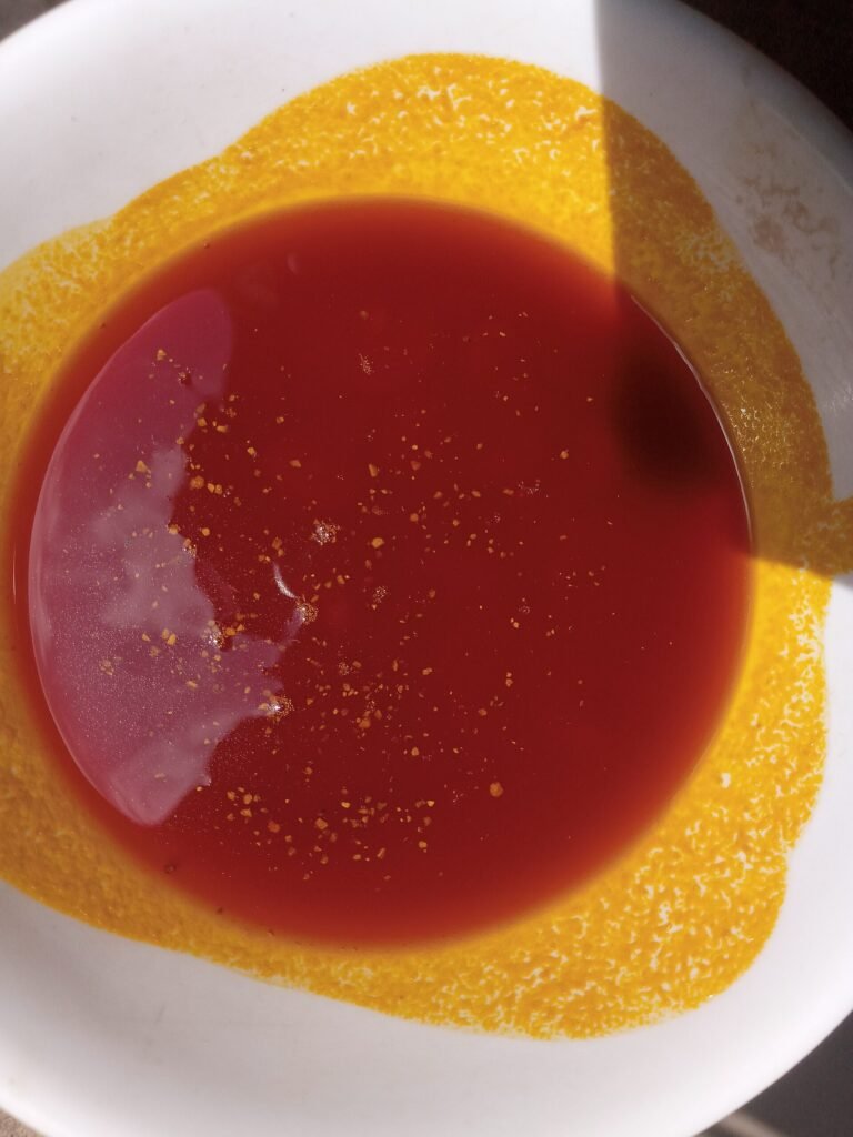 Red palm oil photographed in a white bowl.