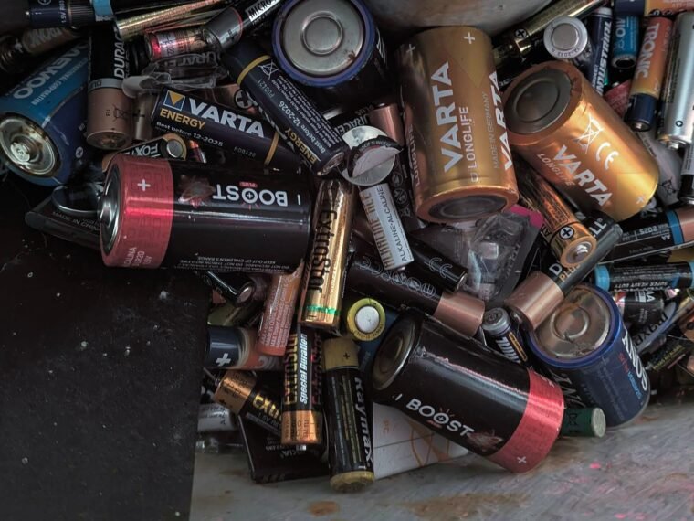 Used household batteries collected inside a recycling container.